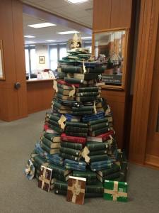Tall green and red Christmas tree constructed from books.